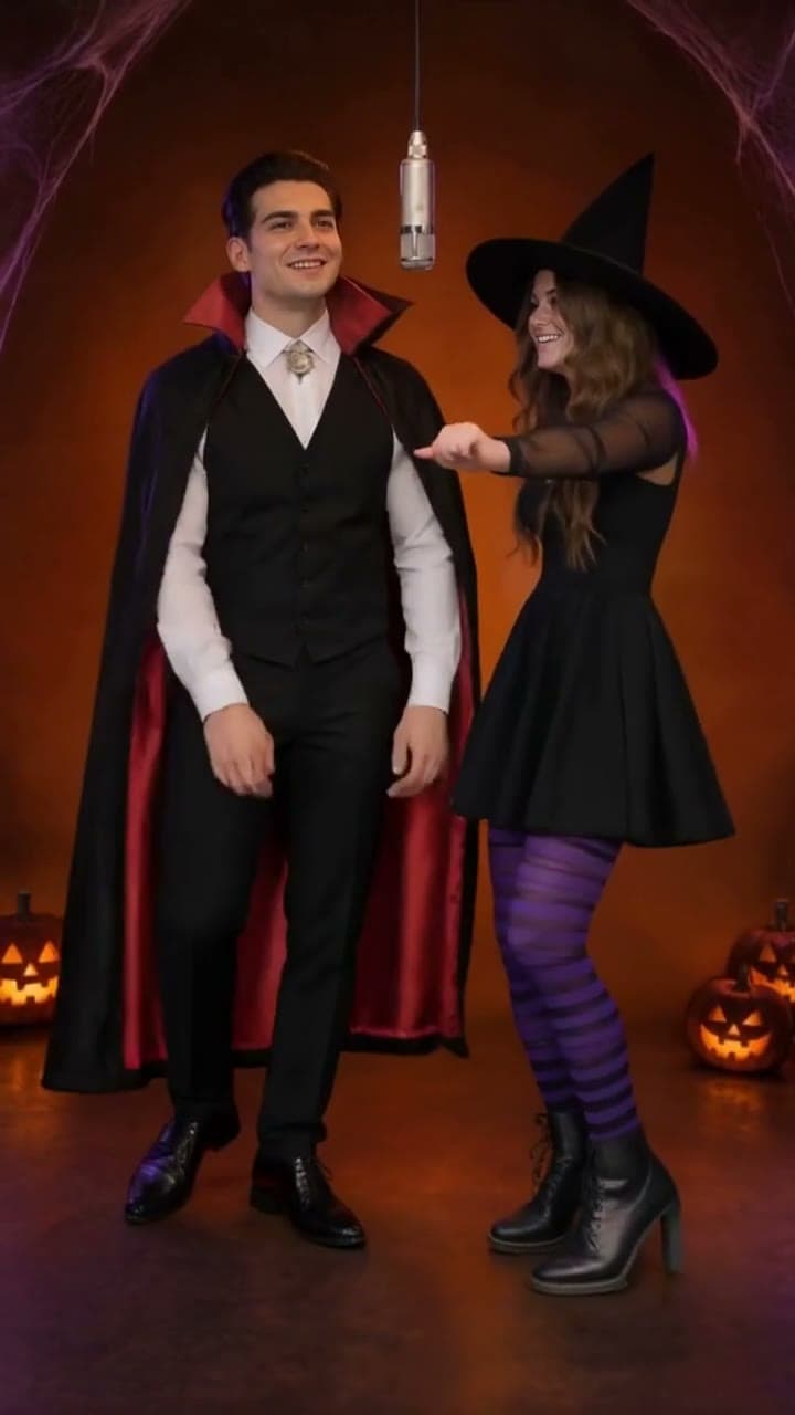A vampire and a witch performing in a Halloween recording booth with glowing pumpkins and cobwebs